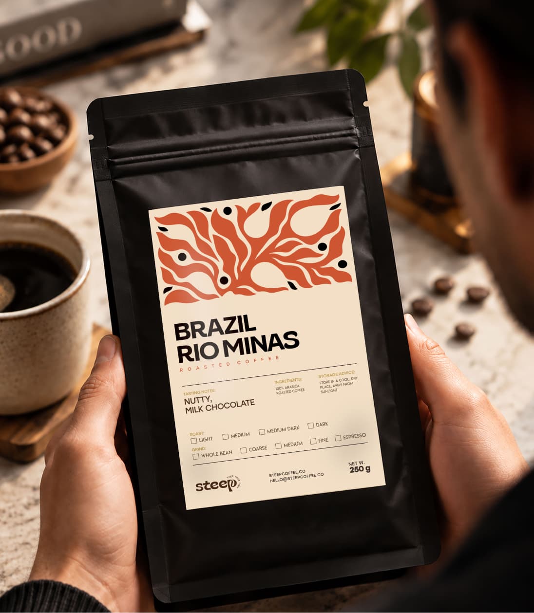 The pouch held in two hands beside a cup of black coffee